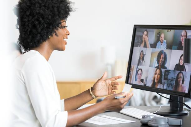 Female financial advisor gestures during meeting with company employees Smiling and gesturing during a meeting with the company's employees, the mid adult female financial advisor reviews the numbers on the spreadsheet in front of her. remote working stock pictures, royalty-free photos & images